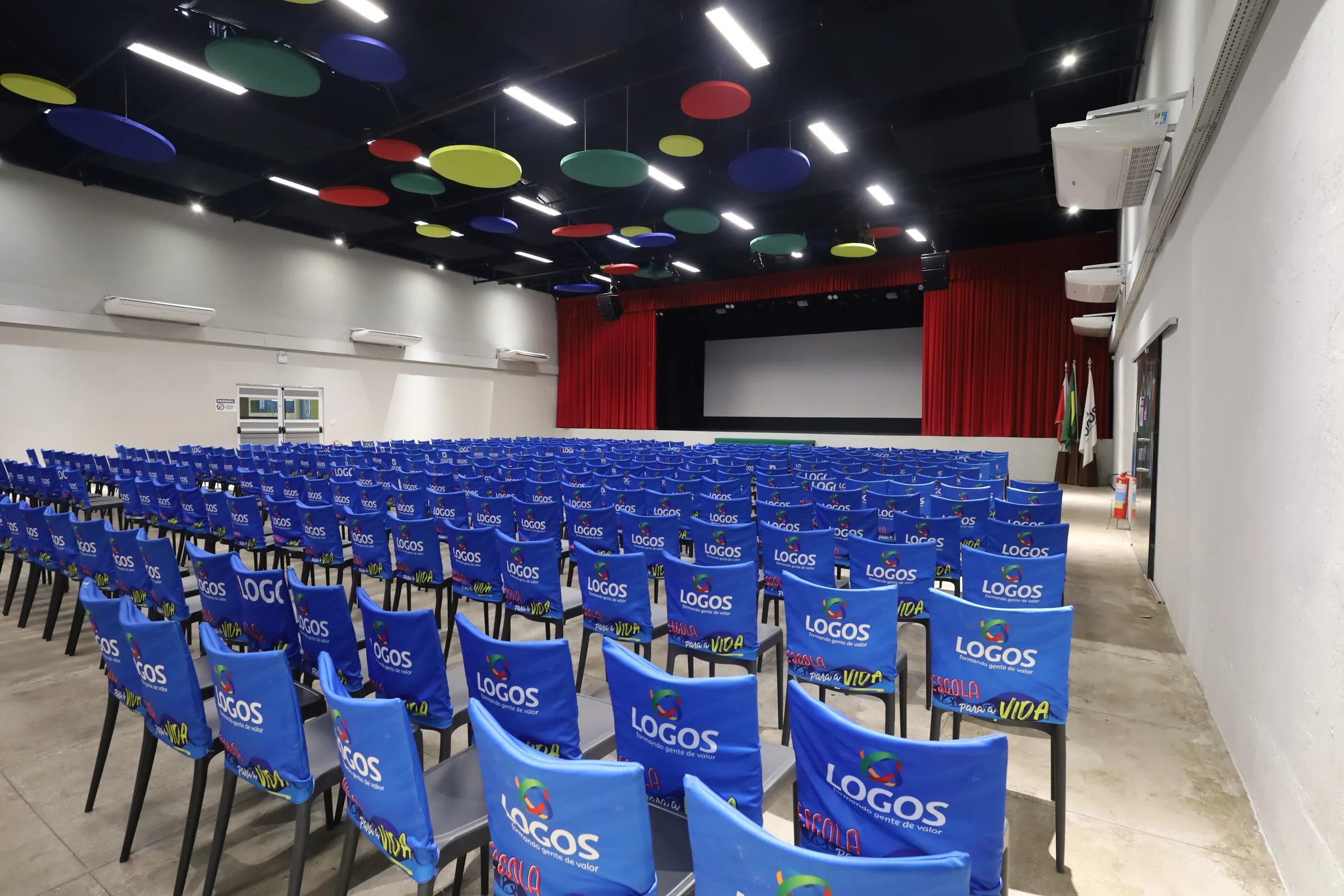 Vista lateral do Auditório principal com palco, tela e assentos